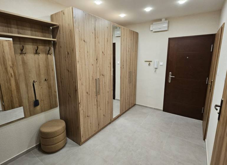 Prenájom 2 izbový byt v Topoľčanoch, sídlisko JUH - Chodba v 2-izbovom byte s nábytkom s dreveným dekorom a vstavaným zrkadlom.