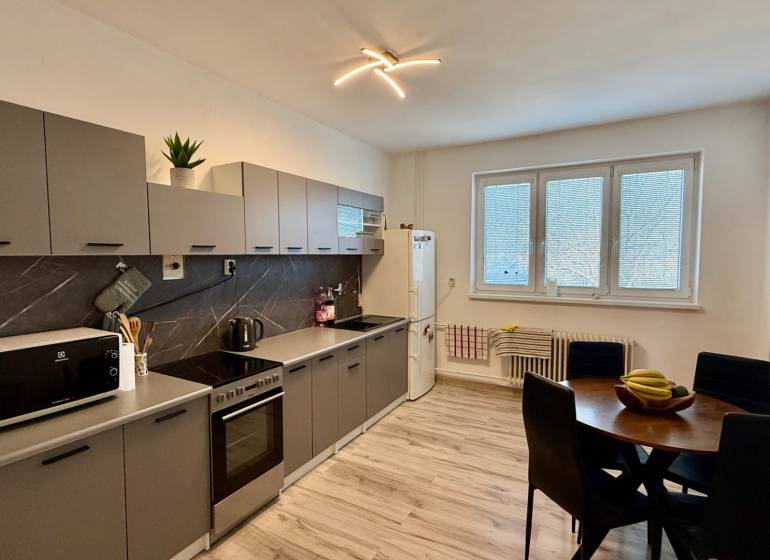 * 7i rodinný dom, veľký 33.5á pozemok, Brestovany - Kuchyňa s podlahou s dreveným dekorom, sivými skrinkami a jedálenským stolom v Rodinnom dome.