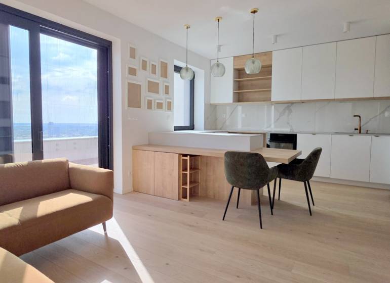 LUXUSNÝ 3i byt,PARKING,CHLADENIE,TERASA,Grand Koliba, Frankovská ulica - Obývacia izba s kuchyňou v 3-izbovom byte ponúka veľké okná a moderný dizajn.