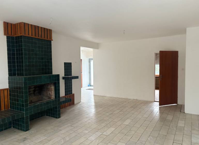 PREDAJ - Rodinný dom s investičným potenciálom - Nové Zámky - Interiér rodinného domu s krbom a podlahou s dreveným dekorom.