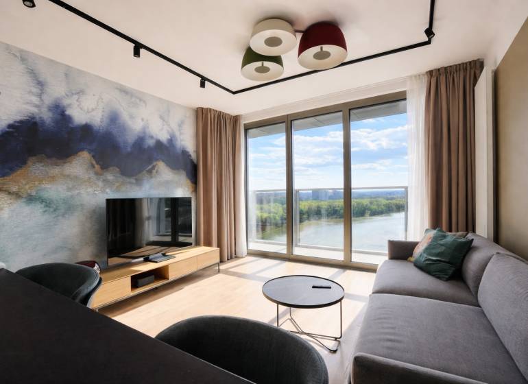 Prenájom 2-izbový byt s loggiou,55m2, EUROVEA TOWER - Obývačka v 2-izbovom byte s výhľadom na rieku a podlahou s dreveným dekorom.