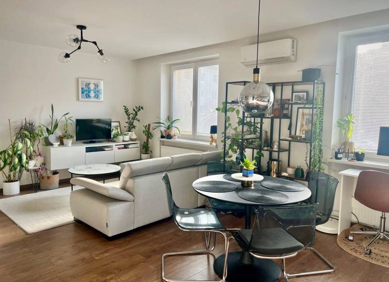 Prenájom 2,5 izbový byt, Trenčianska ulica, Bratislava II. Ružinov - Obývačka v 2-izbovom byte s podlahou s dreveným dekorom a množstvom rastlín.