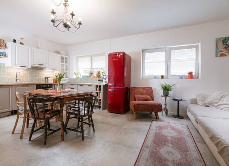 Na predaj zrekonštruovaný dom na Štefánikovej ulici, Trenčín - Kuchyňa v rodinnom dome s bielymi skrinkami, červenou chladničkou a dreveným stolom.