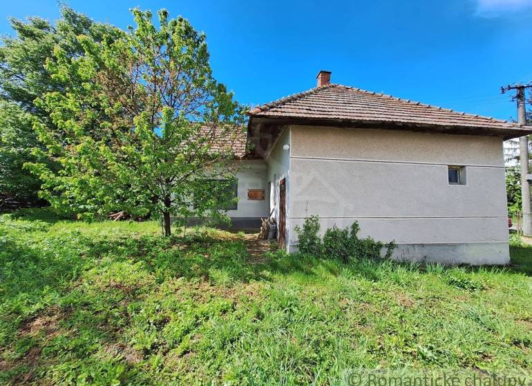 Pôvodný domček v obci Nová Vieska - Rodinný dom v Novej Vieske obkolesený zeleňou a stromami, s tradičnou strechou.