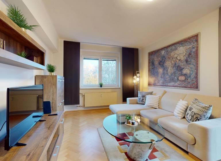 BA/STARÉ MESTO - Prenájom kompletne zariadeného 2i bytu s 2 balkónmi - Obývacia izba v 2-izbovom byte s pohovkou, TV a podlahou s dreveným dekorom.