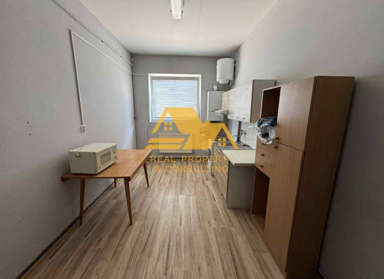 Prenajmem garsónku v Nesvadoch - Jednoduché zariadenie garsónky s kuchynským kútom a podlahou s dreveným dekorom.