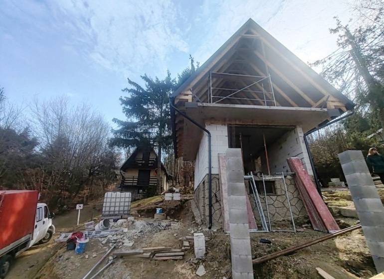 RO Domaša Zajačia Debra - Chata pri vode! - Stavba chaty na Zajačej debre v Holčíkovciach obklopená stromami a stavebným materiálom.