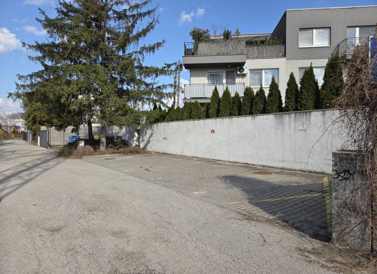 Parkovacie státie v Ružinove – pri Gymnáziu I. Horvátha a električke - Garáže na Vavrínovej ulici v Bratislave - Ružinove s okolitou zeleňou a domami.