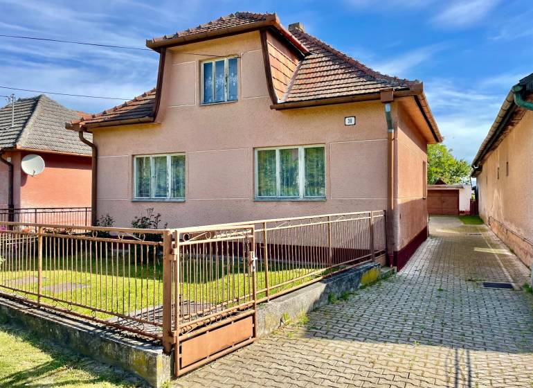 Rodinný dom s veľkým pozemkom a garážou, Dvorec - Rodinný dom vo Dvorci so šikmou strechou a vstupnou bránou.