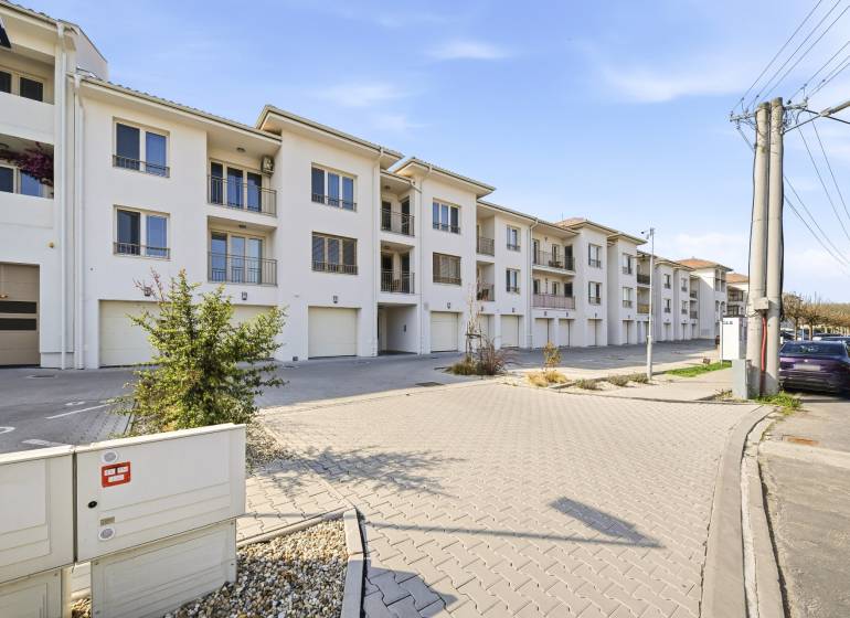 Na predaj 4-izb.byt s 2 terasami a garážou, Dun.Streda - Exteriér 4-izbového bytu v Dunajskej Strede so svetlou fasádou a garážami.