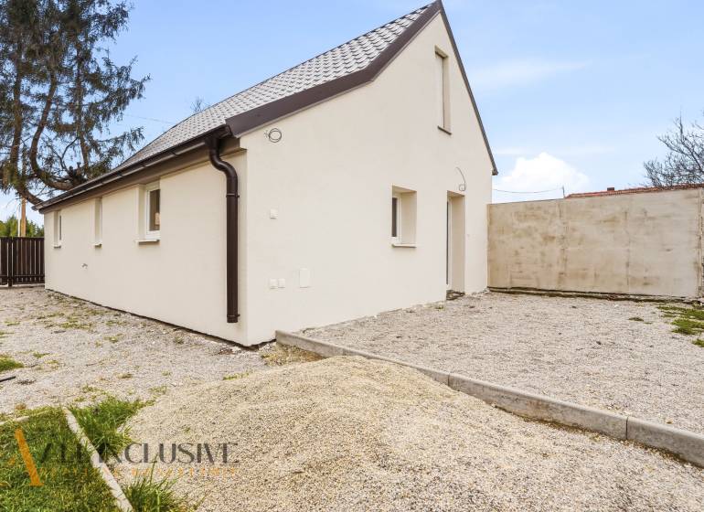 Na predaj 2,5-izbový rodinný dom, Dolný Bar - Rodinný dom v Dolnom Bare s bielou fasádou a šikmou strechou na štrkovom pozemku.
