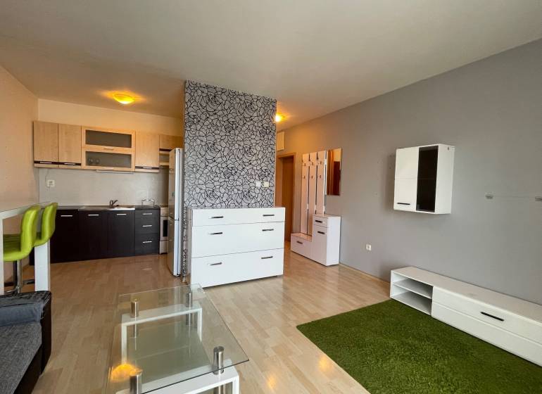 Prenájom 1 izbový byt v Galante, Hodská - Obývačka v 1-izbovom byte s kuchynským kútom a podlahou s dreveným dekorom.