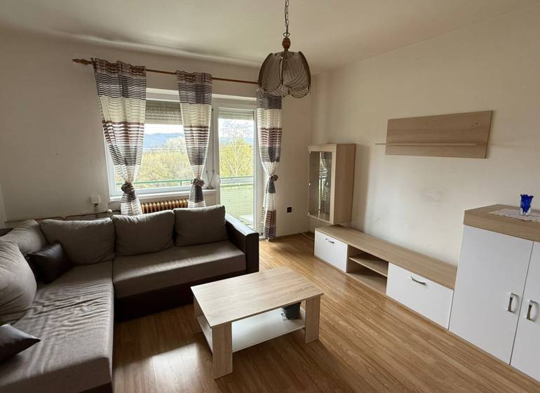 Na predaj 3i byt Pukanec - Obývačka v 3-izbovom byte s pohodlnou sedačkou, podlahou s dreveným dekorom a balkónom.