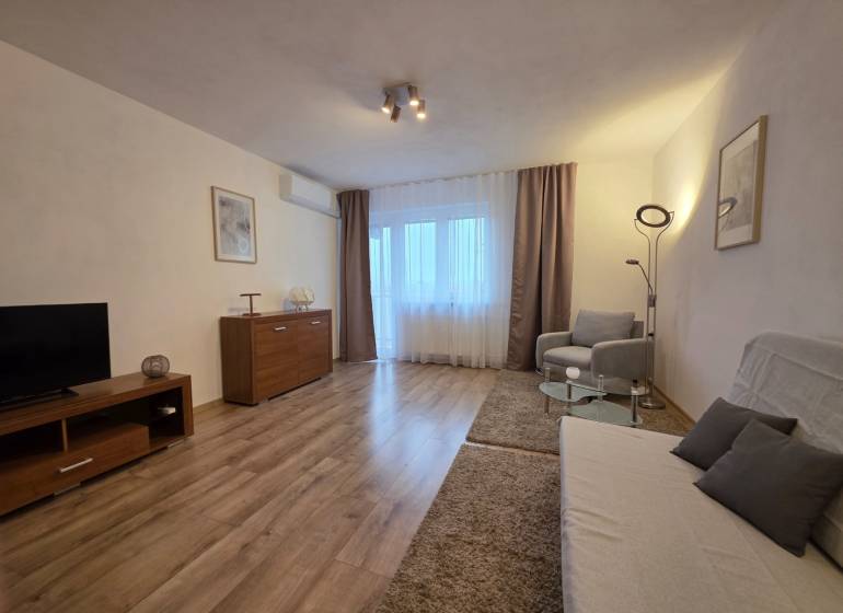 PRENÁJOM - Priestranný 3 izbový byt - Nitra, Centrum - Obývacia izba v 3-izbovom byte s podlahou s dreveným dekorom a pohodlným nábytkom.