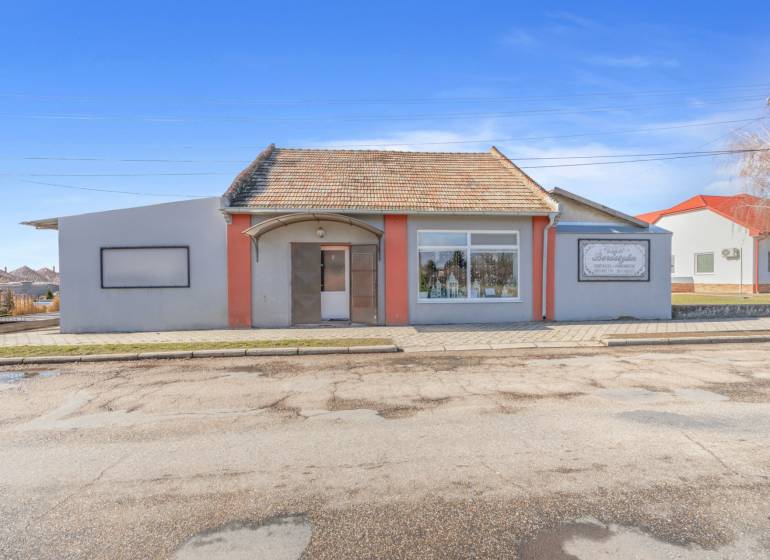 Komerčný objekt s pozemkom – možnosť zmeny na rodinný dom - Obchodné priestory v meste Okoč s výkladnými oknami a šikmou strechou.