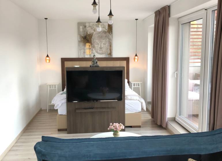 Na predaj štyri apartmány na jednom poschodí Podhájská - Obývacia izba v 2-izbovom byte s podlahou s dreveným dekorom a oddelenou spálňovou zónou.