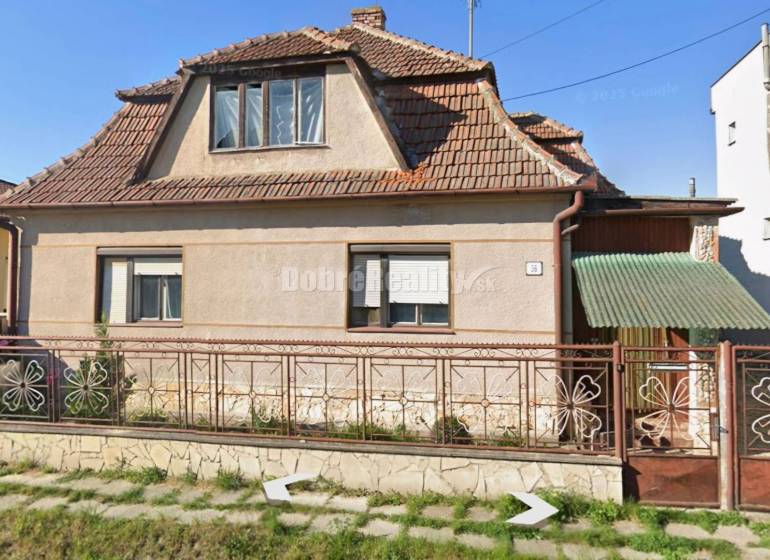 Na predaj rodinny dom v obci Iža. - Rodinný dom v Iži s tradičnou strechou a kvetinovým plotom.