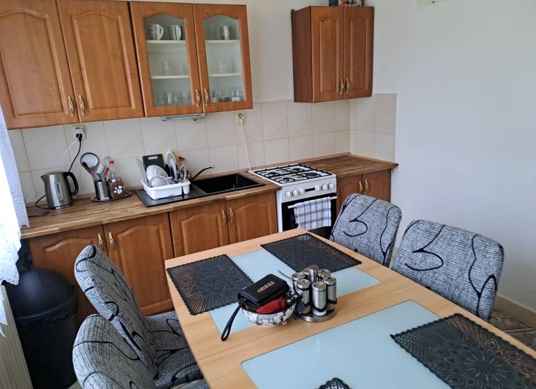 Predaj čiastočne prerobený 3 izbový byt Martin Sever - Kuchyňa s jedálenským stolom v 3-izbovom byte, drevené skrinky a sporák.