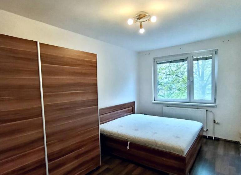 Predaj 4-izbového bytu na začiatku Petržalky Bratislava V - Spálňa so skriňou, posteľou a podlahou s dreveným dekorom v 4-izbovom byte.