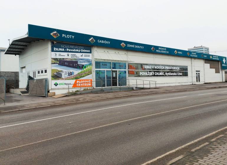 PRENÁJOM: Moderná hala (525 m²) v TOP lokalite Žiliny – Kamenná ul. - Obchodné priestory na Kamennej ulici v Žiline s reklamnými nápismi a prázdnym parkoviskom.