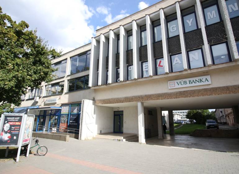 Prenájom centrum Galanty - Budova s kanceláriami a bankou v Galante, so stromom a chodníkom v popredí.