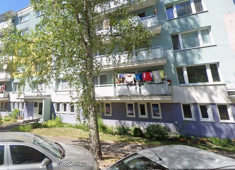 Kúpime  2izbový byt, Beskydská ul. 7,9,11, Banská Bystrica - Bytový dom na Beskydskej 9 v Banskej Bystrici so zeleňou a ženou vpredu.