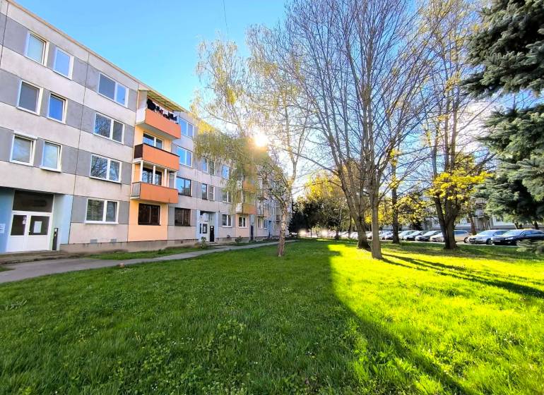 ‼️ PARTIZÁNSKE - 3,5 IZBOVÝ BYT NA PREDAJ, VEĽKÁ OKRUŽNÁ ‼️ - Panelový dom na Veľkej Okružnej v Partizánskom obklopený zeleňou a zaparkovanými autami.