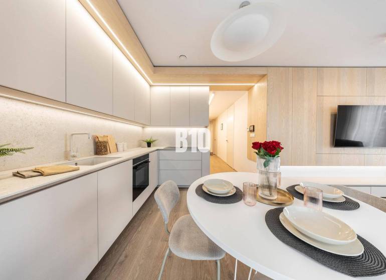 LUXUSNÝ 3-IZBOVÝ BYT NA MIERU V NADČASOVEJ NOVOSTAVBE NA ZAČIATKU KOLI - Štýlová kuchyňa v 3-izbovom byte s podlahou s dreveným dekorom a moderným nábytkom.