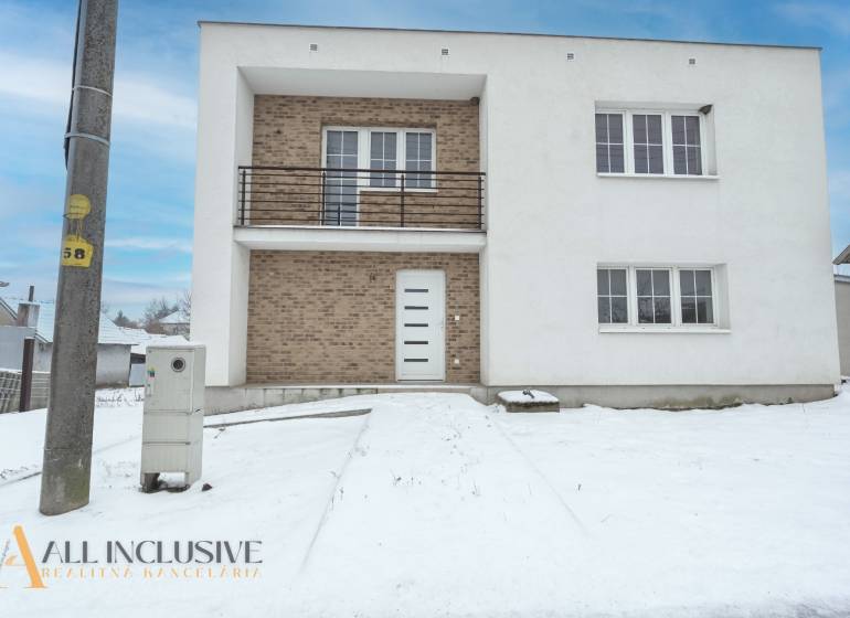 Na predaj poschodový 6-izbový rodinný dom, Horné Mýto - Rodinný dom v Hornom Mýte so snehovou pokrývkou a tehlovými detailmi na fasáde.