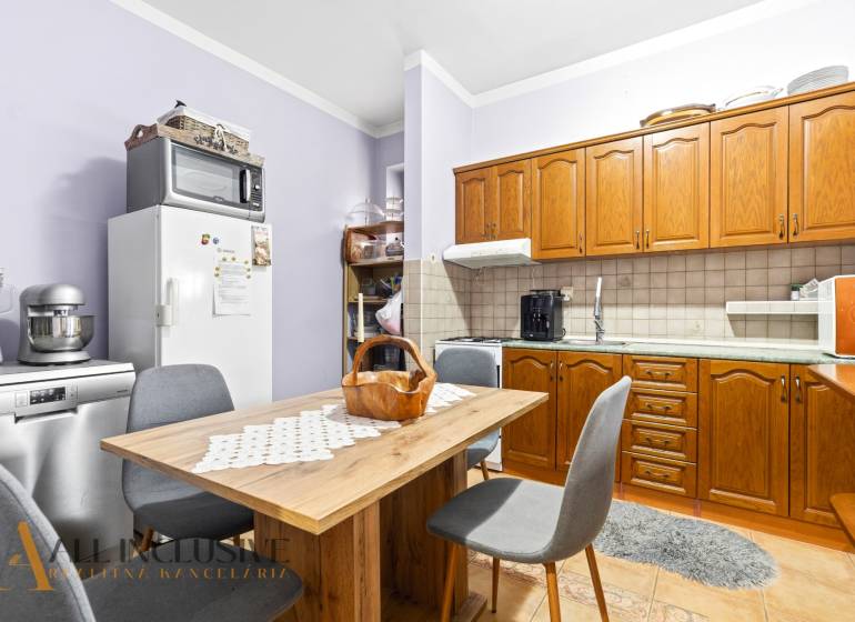 Na predaj zrekonštr.4-izb. rodinný dom, Čečínska Potôň - Kuchyňa v rodinnom dome s drevenými skriňami, stolom a stoličkami, spotrebiče na doske.