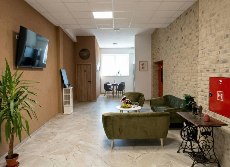 Prenájom klimatizovaná kancelária: 25 m2 a 42 m2 - Trnava Chovateľská - Kancelárie s pohodlným sedením, rastlinou a televíziou, podlaha s dreveným dekorom.