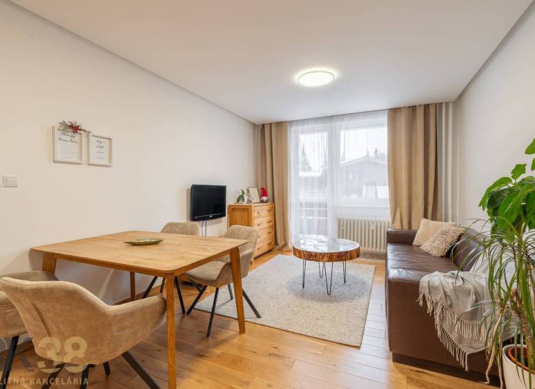 Exkluzívny byt v srdci Vysokých Tatier na Štrbskom Plese - Obývacia izba v rekreačnom apartmáne s útulnou pohovkou a podlahou s dreveným dekorom.