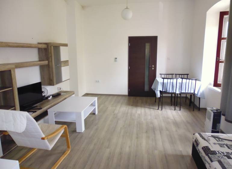 PRENÁJOM: HLAVNÁ - VOĽNÝ 2,5-izbový byt + kuchyňa, kúpeľňa, WC  - Obývacia izba v 3-izbovom byte so svetlým nábytkom a podlahou s dreveným dekorom.