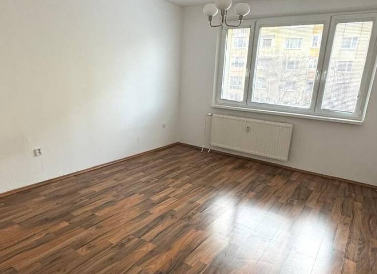 1-izb. byt, J.Stanislava, Karlova Ves, lodžia, 3.p./8 - Priestranná izba s podlahou s dreveným dekorom a veľkým oknom v 1-izbovom byte.