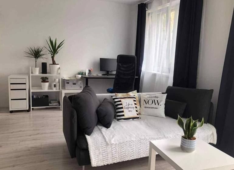 1,5 izb. byt s predzáhradkou, Podunajské Biskupice, projekt Oppidum - Obývacia izba v 2-izbovom byte s tmavými závesmi a dekoratívnymi vankúšmi.