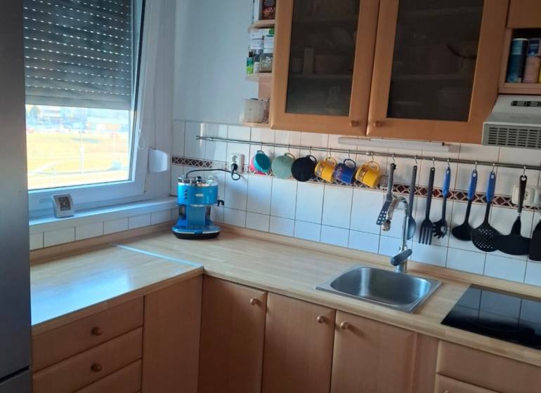 Dvojgarzónka DELUXE, začiatok Petržalky - Kuchyňa v 2-izbovom byte s dreveným dekorom a modrým kávovarom.