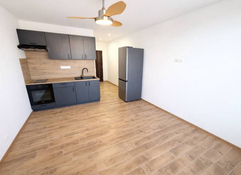 NA PRENÁJOM GARSÓNKA S BALKÓNOM, SENICA, ŠTEFÁNIKOVA UL. - Garsónka s kuchynskou linkou a podlahou s dreveným dekorom, chladnička.