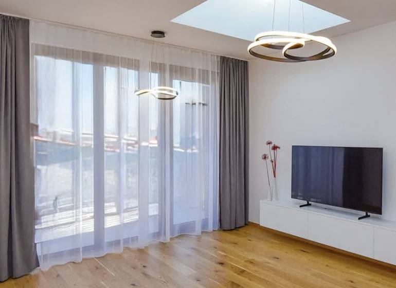 Na predaj: CENTRUM 2 izb.byt po kompletnej novej rekonštrukcii - Obývacia izba v 2-izbovom byte s televízorom a podlahou s dreveným dekorom.