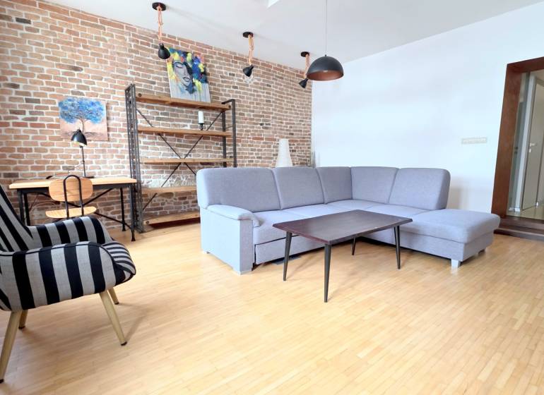 JEDINEČNÝ 2i byt, REKONŠT., 2 X .SAMOST.IZBA, Hviezdoslavovo nám.  - Obývacia izba v 2-izbovom byte s tehlovou stenou a podlahou s dreveným dekorom.