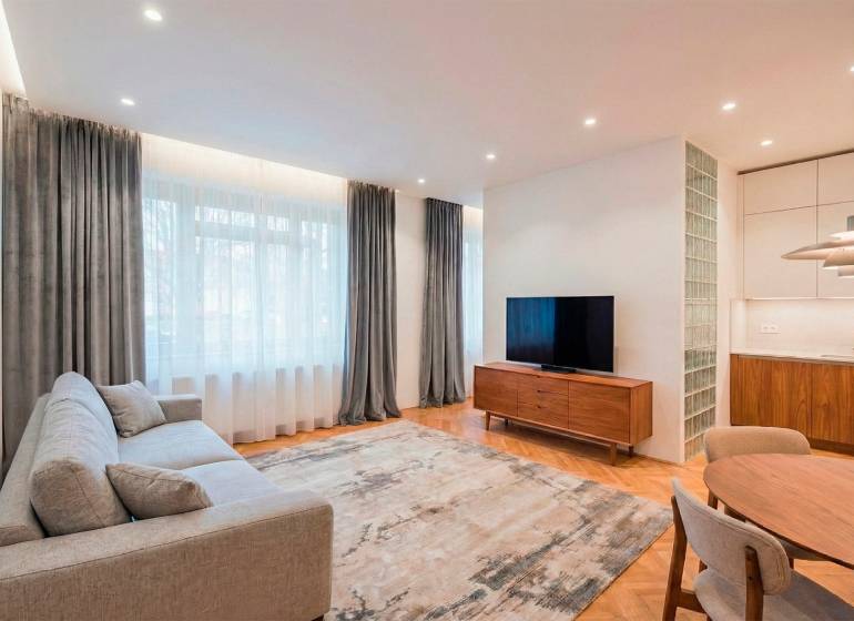 NA PREDAJ štýlový byt v centre Nitry  - Obývačka so sedačkou, televízorom a podlahou s dreveným dekorom v 3-izbovom byte.