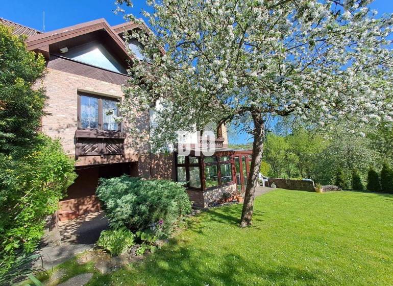 Zaujímavý rodinný dom s veľkým pozemkom, krásnou záhradou a bohatým pr - Rodinný dom v Lietave obklopený záhradou s kvitnúcimi stromami a trávnikom.