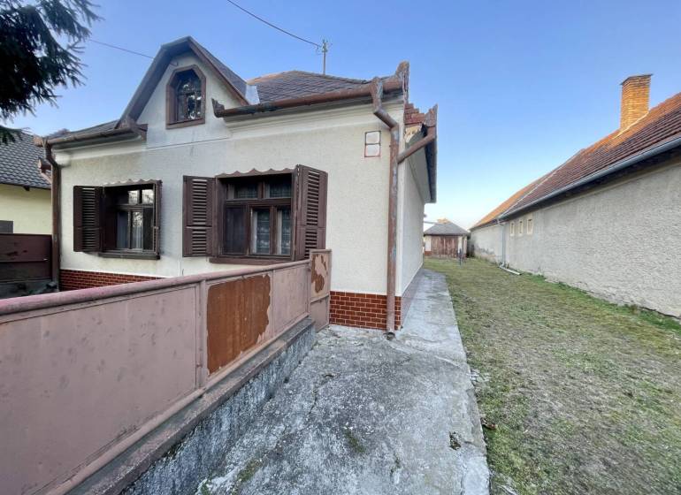 TOPOĽNÍKY – 4-IZBOVÝ RODINNÝ DOM NA PREDAJ NA 14 ÁROVOM POZEMKU - Rodinný dom na Hlavnej ulici v Topoľníkoch s drevenými okenicami a terasou.