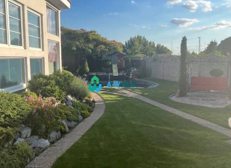 Znížená cena!  Rodinný dom s vnútorným aj vonkajším bazénom na krásne  - Pokojná záhrada pri rodinnom dome, s udržiavaným trávnikom, kvetinovými záhonmi a chodníkom.