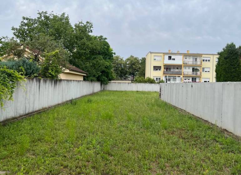Stavebný pozemok na Poľnej ulici. - Pozemok na ulici Poľná oplotený betónovým plotom, s výhľadom na bývanie.