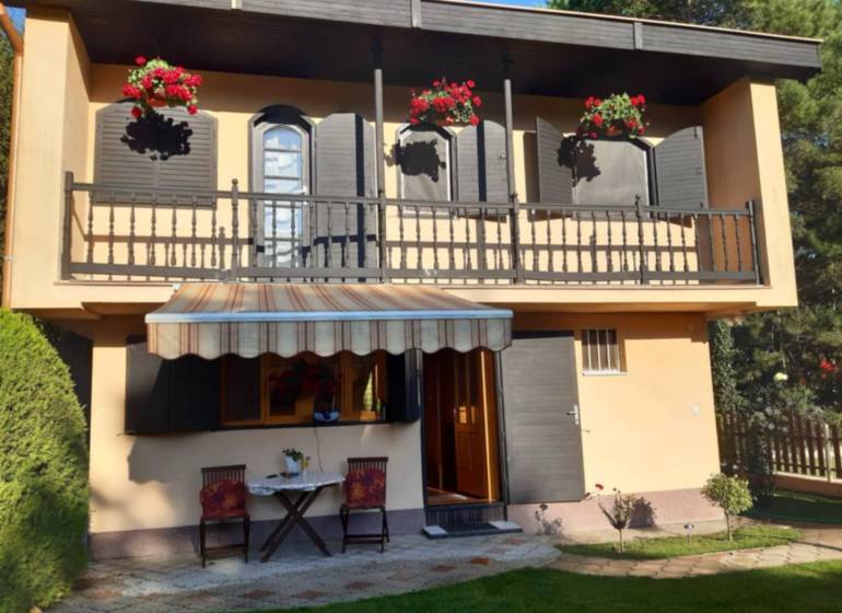 Rodinný  dom na predaj v Gabčíkove - Rodinný dom v Gabčíkove s balkónom, kvetmi, altánkom a dvoma stoličkami na trávniku.