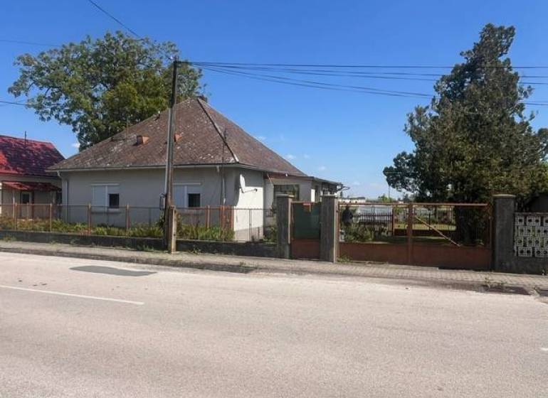 Rodinný dom na úžasnom pozemku. - Rodinný dom v Kráľovičových Kračanoch s oplotením, stromami a cestou v popredí.
