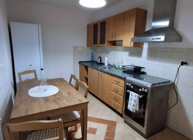 ☎️   0918 846 340           Byt v centre mesta na Jesenského ulici. - Kuchyňa v 1-izbovom byte s dreveným nábytkom, sporákom a podlahou so vzorom.