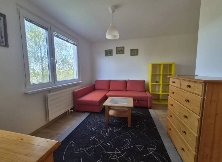 REZERVOVANÉ! Zariadená garsónka po kompletnej rekonštrukcii - Obývacia izba Rekreačného apartmánu s červenou pohovkou, žltou policou a podlahou s dreveným dekorom.