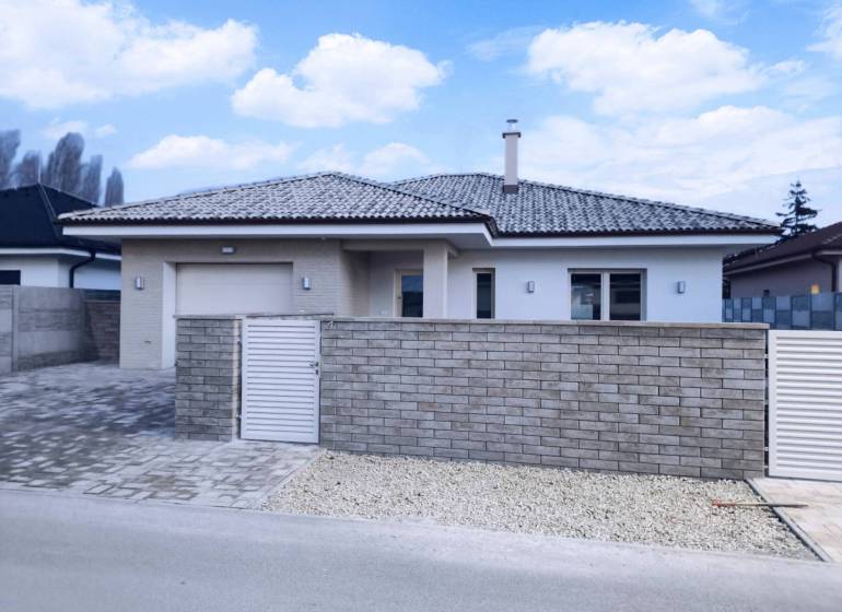 Rezervované / 4-izbový rodinný dom v obci Michal na Ostrove - Rodinný dom v Michal na Ostrove so strechou a plotom z tehál.