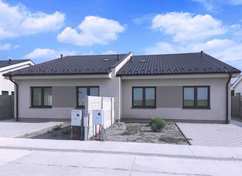 Predané - 4izbový rodinný dom (dvojdom) v obci Horná Potôň! - Dom v Hornej Potôni s tmavou strechou, dvomi oknami a priľahlou príjazdovou cestou.